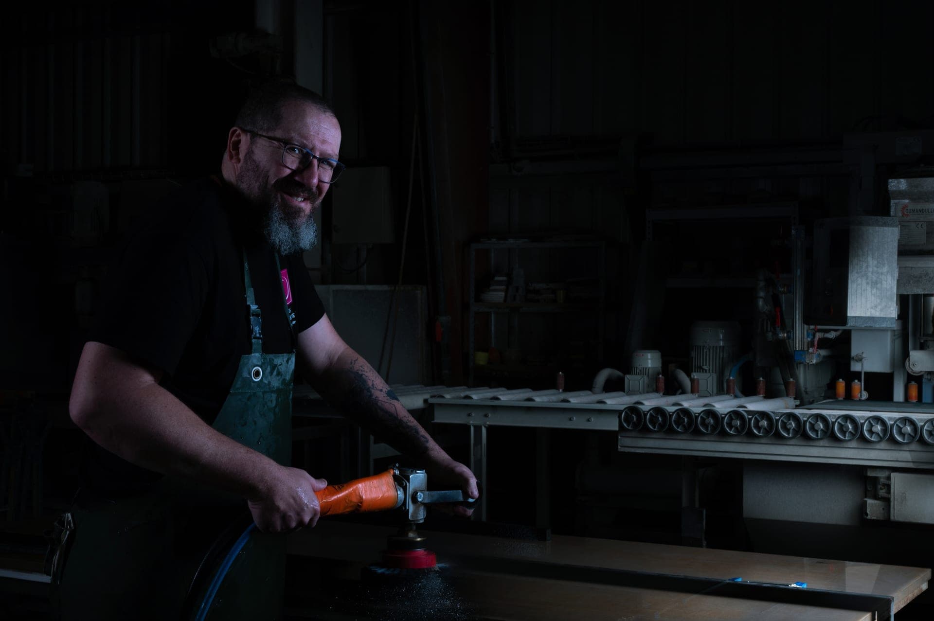 Artisan Decottegnie à la ponceuse sur une tranche de marbre dans l'atelier de Mouvaux