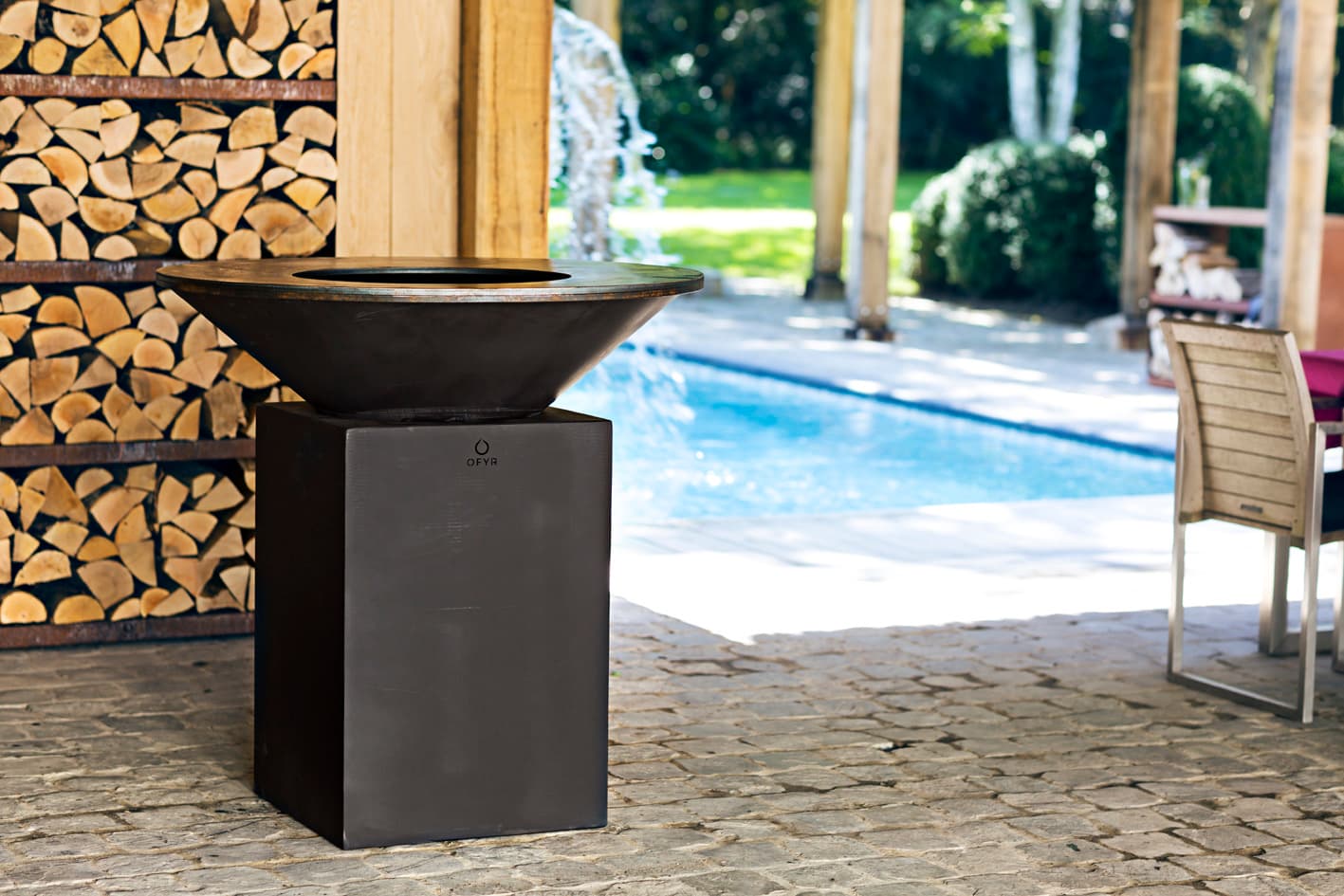 Barbecue OFYR installé au bord d'une piscine, terrasse extérieure