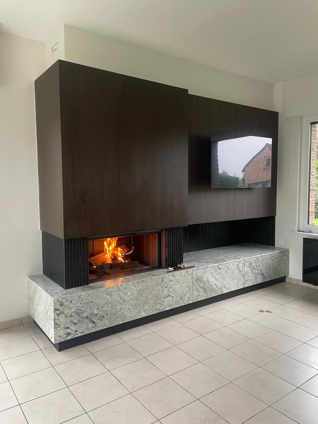 Habillage de cheminée en bois avec socle en granit et mur TV — réalisation Decottegnie