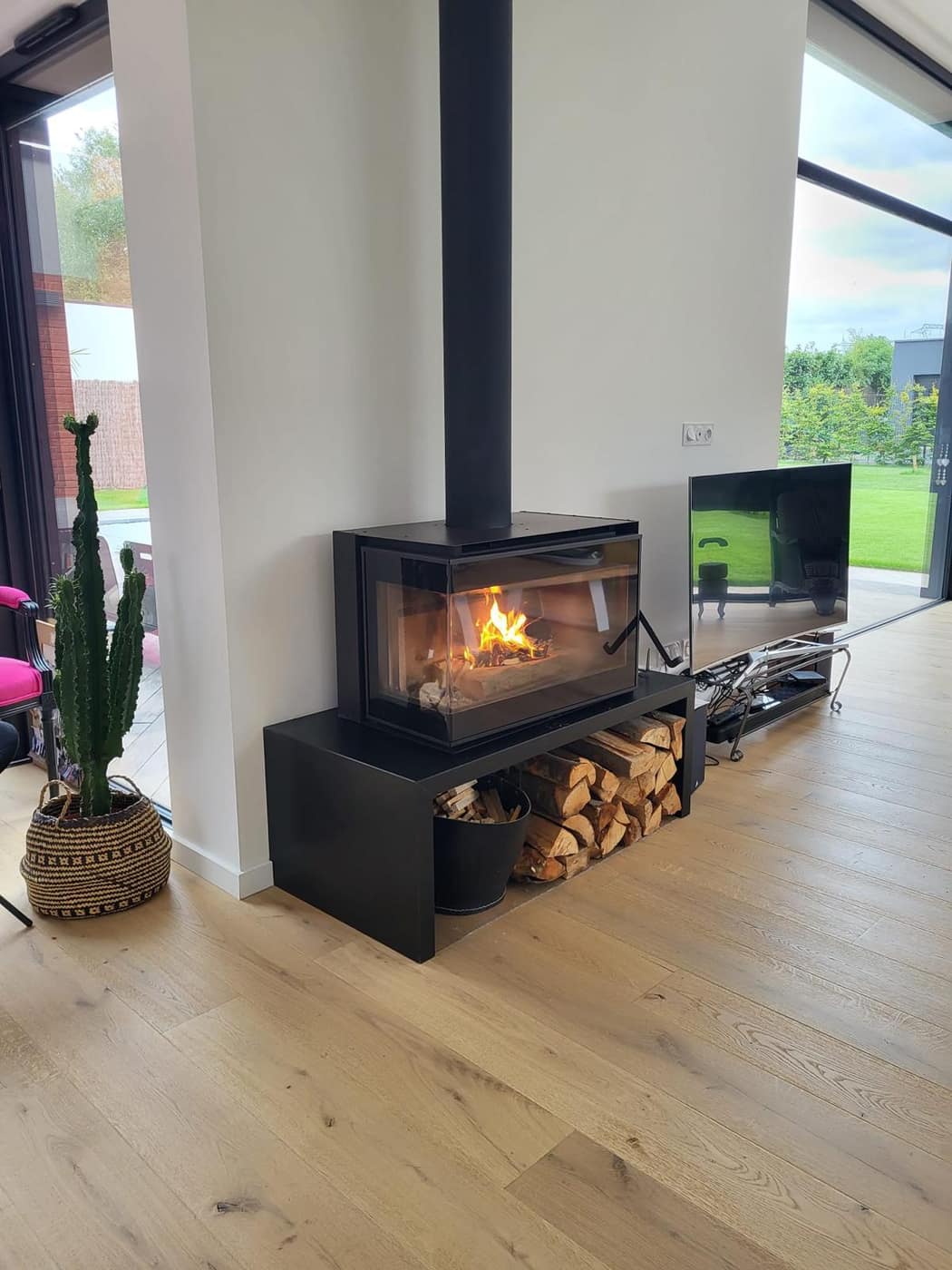 Poêle à bois sur banc acier avec rangement bûches — installation Decottegnie